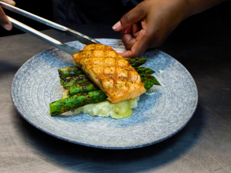 Chef plating grilled salmon with asparagus for Visit Orlando Magical Dining