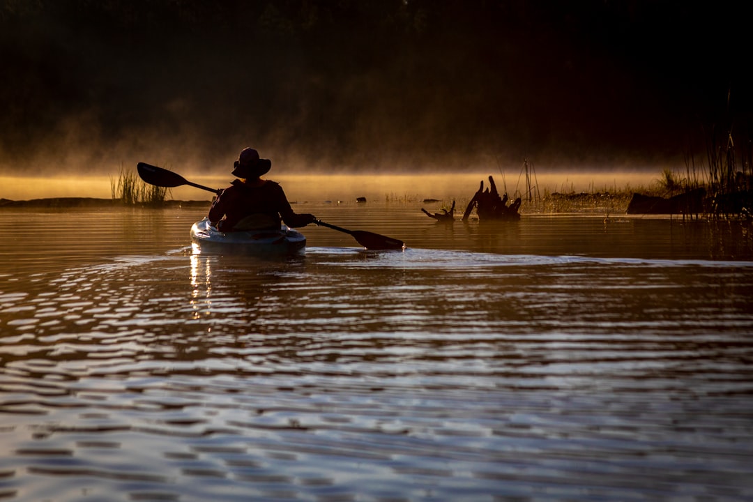 Kayaker paddling a calm lake at dusk