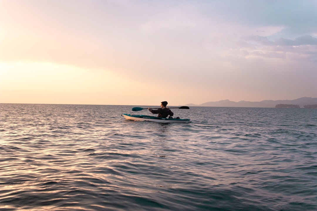 Person kayaking on a calm lake in the morning
