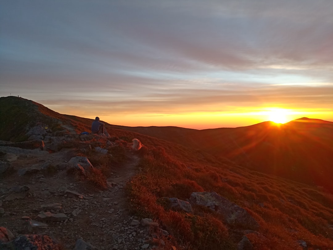 Hiker watching the sunset from a hilltop trail